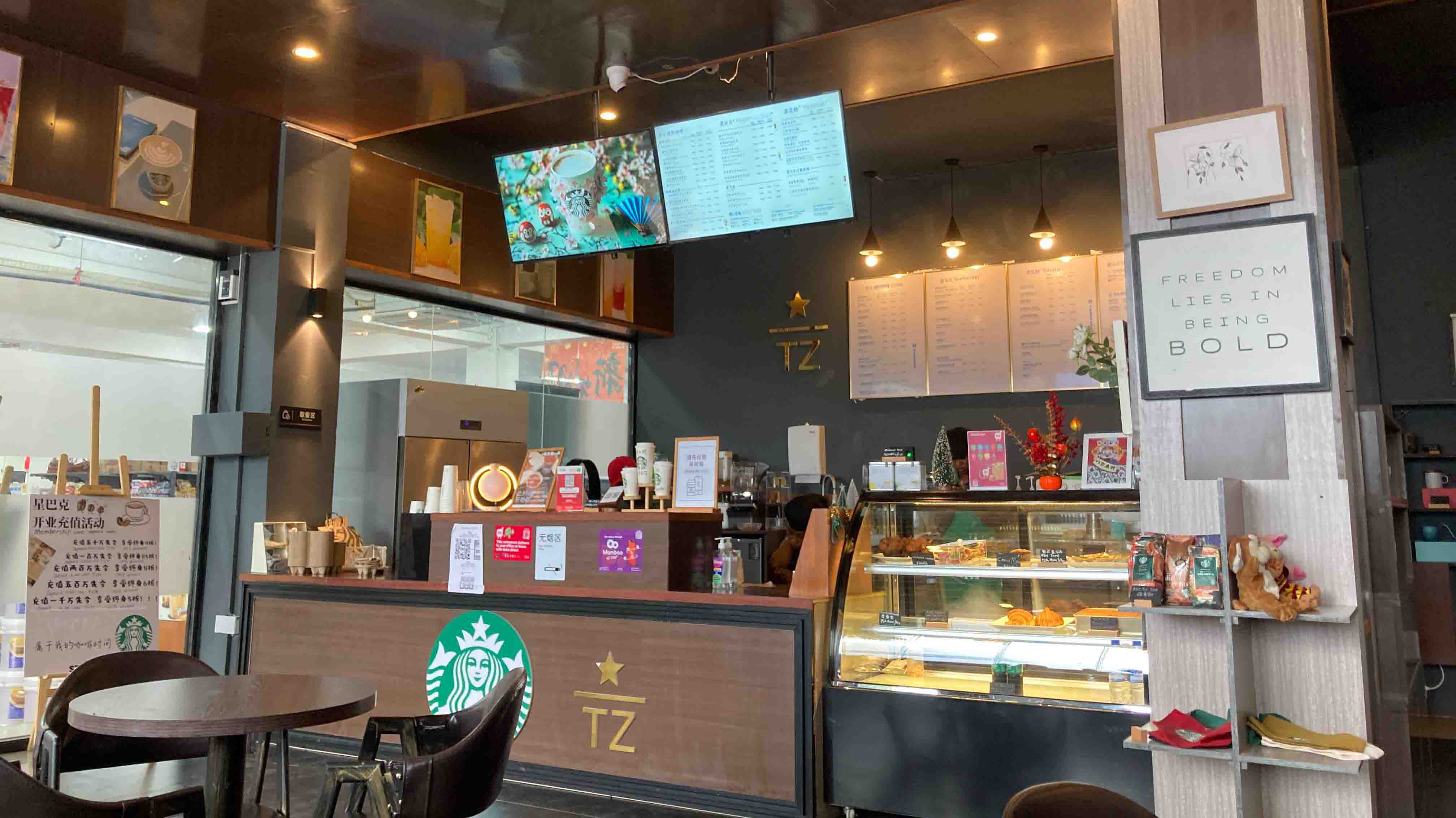 Interior view of the Starbucks with the ordering counter, menu boards, baked goods display, and seating area.