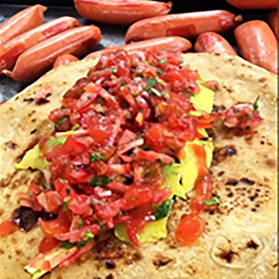 チャパティの上にアボカドと刻みたてのカチュンバリがのり、周囲にソーセージが並べられている。