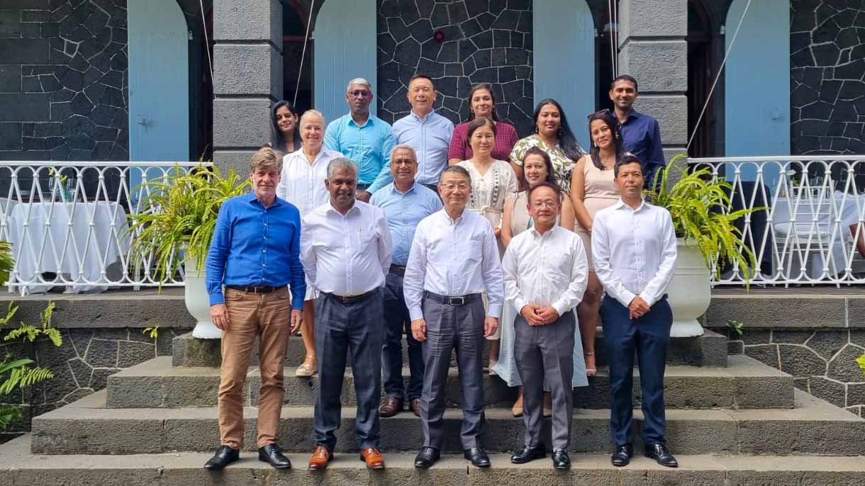 Group photo of MOL Chairman, MCT Enforcers, i61 Foundation members, and other partners standing together outside a historic stone building in Mauritius.